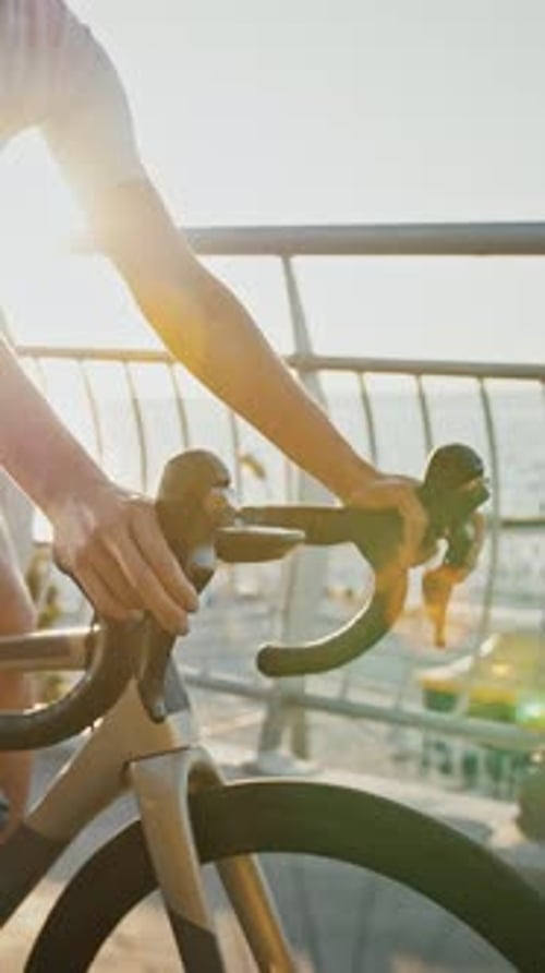 Une femme inconnue en vêtements de sport fait du vélo moderne en descente le long d'un pont près d'une côte