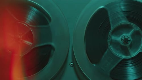 Rotating Reels of Old Analog Tape Recorder in Blue Neon Light