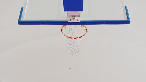 A basketball swishes through the hoop in slow motion from a low-angle perspective