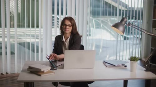 Young Businesswoman In Suit Working On Laptop In Modern Open Office Workspace