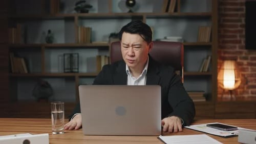 Frustrated Businessman Closing Laptop at Office Desk