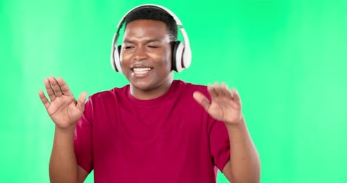 Headphones, dance and black man on green screen studio, music and singing online audio