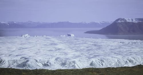 Expansive View of Frozen Landscape with Mountains and Ocean in the Background