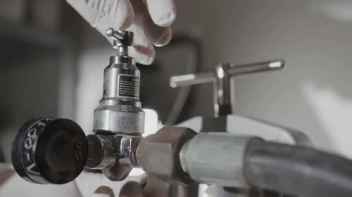 Hand Turns Lever to Pump Gas Inside System at Plant