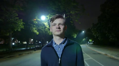 Young Man Walking on Street Alone in Dark Night