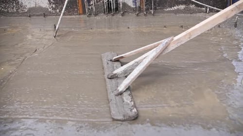 Worker at a Construction Site Leveling Poured Concrete