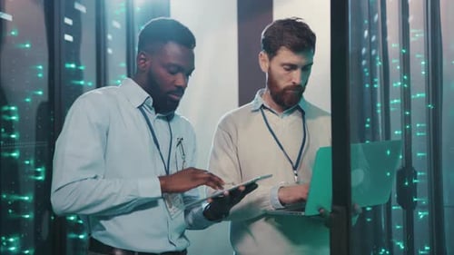 IT workers in futuristic server room use laptop