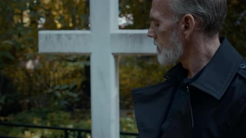 Bereaved Middle-Aged Man Standing by Grave in Cemetery