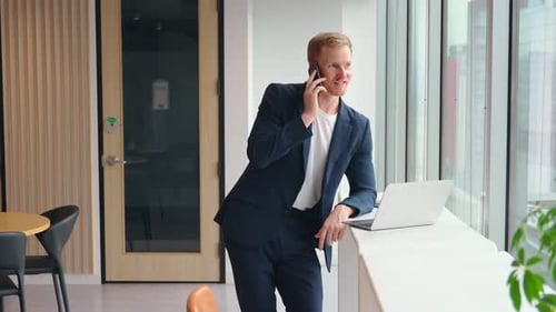 Busy Professional Business Man Using Laptop Talking on Phone in Office