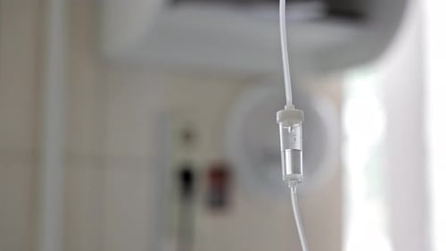 Close Up View of the Intravenous Drip Chamber with Liquid Medicine Drops Medical Infusion System in