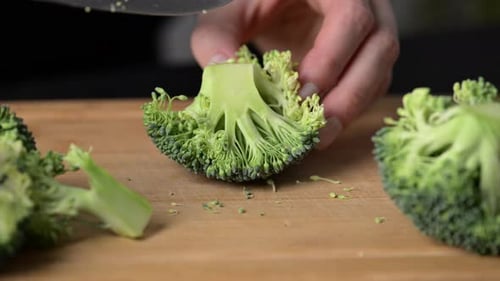 Person Cuts Fresh Broccoli with Sharp Knife