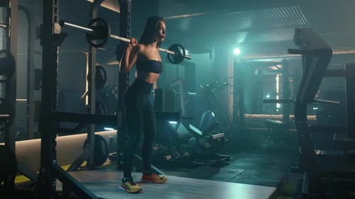 Young Female Athlete Performing Squats with a Barbell in a Wellequipped Gym