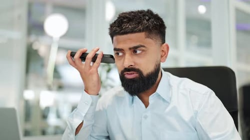 Focused Businessman Listening Intently to a Phone Call in a Modern Office