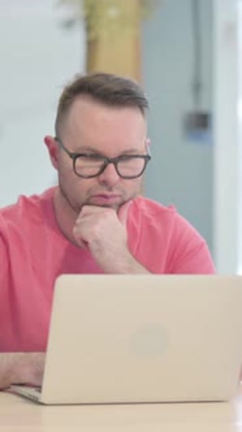 Man Wearing Glasses Using Laptop and Thinking