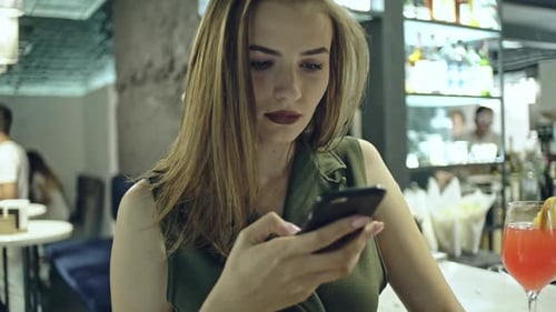 Chica surfeando el teléfono en el bar
