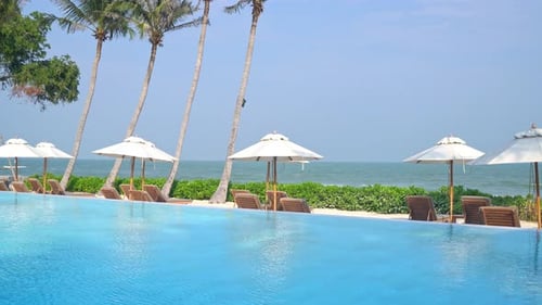 umbrella with bed pool around swimming pool with ocean sea background - holiday and vacation concept