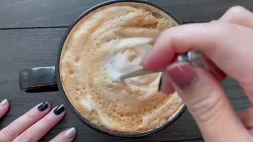 Woman stirring a hot cup of pumpkin spice latte. Autumn mood.