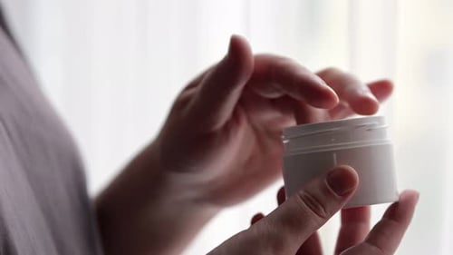 Woman Applies Hand Cream from Jar