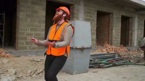 Um engenheiro arquiteto em um canteiro de obras dançando e girando enquanto segura o telefone