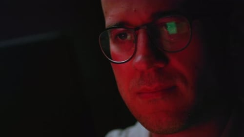 Homme travaillant la nuit en regardant les reflets du moniteur dans ses lunettes Personne négociant en bourse chez