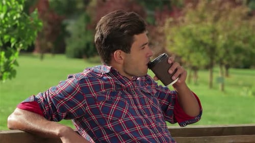 Relaxed Male Enjoying Coffee in a Sunny Park