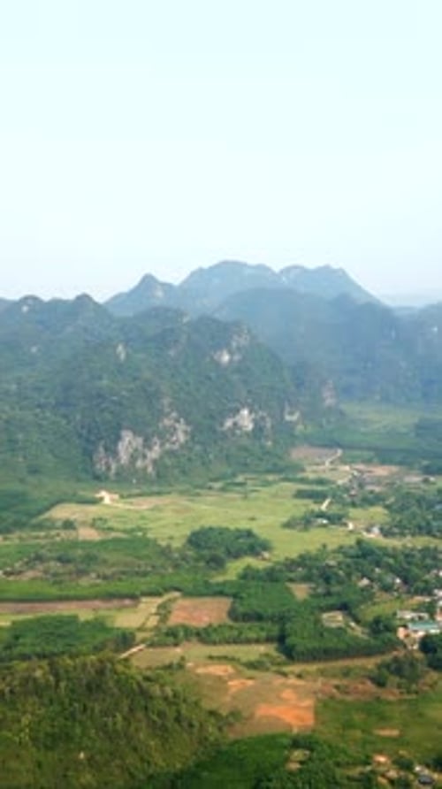 Village on the Plain Surrounded By Large Rocky Mountains and Lots of Vegetation in Vietnam