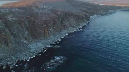 Aerial Landscape of an Ocean Blue Waves Breaking on the Rocks of a High Cliff at the Sunset