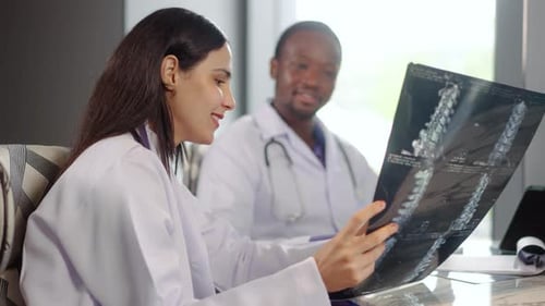 Two diverse doctors collaborate in a hospital, examining test results and discussing X-ray scans