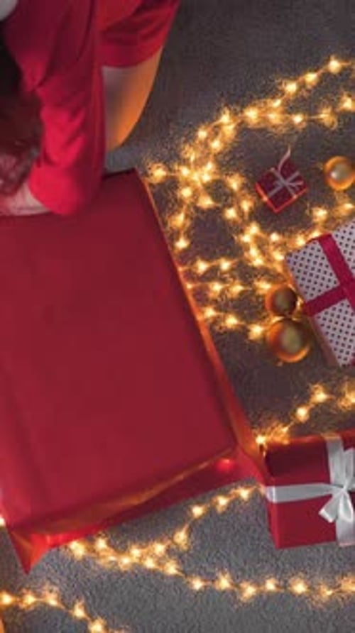 Woman Wrapping Christmas Gift on Illuminated Floor