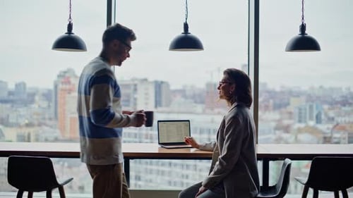 Un homme apporte un café à un collègue, fenêtres panoramiques, espace de coworking, des gens qui parlent