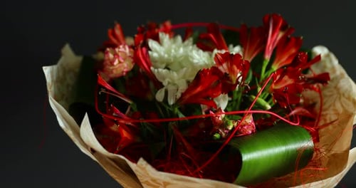 Spinning around a large bouquet of red and white flowers and green decorative elements in a glass va