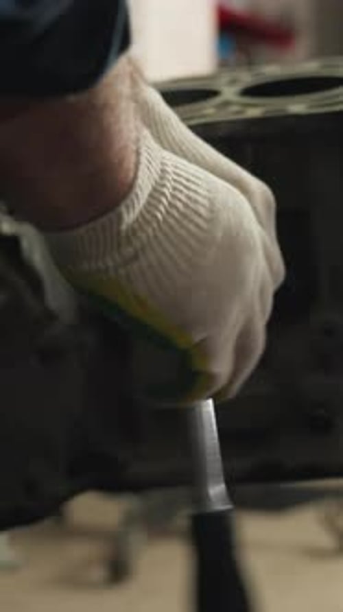 CloseUp of Mechanics Scraping and Loosening Bolt on Car Engine in Workshop