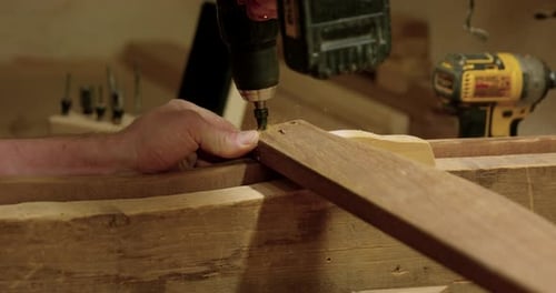 Man drilling hole into wood jig - close up on hands and drill bit