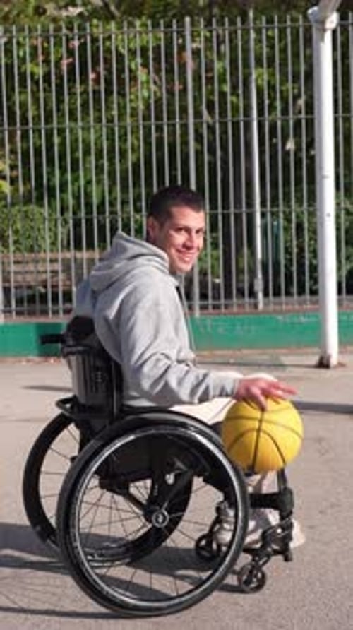 Man in Wheelchair Dribbles Basketball on Outdoor Court