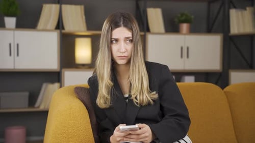 Sad Woman on Couch Uses Smartphone