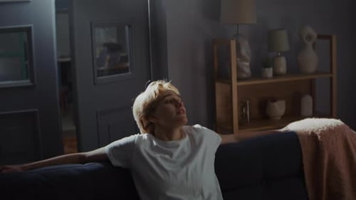 Young Woman Experiences Emotional Distress Sitting on Couch