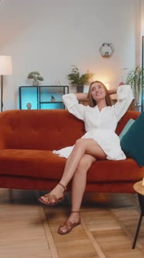 Young Woman Relaxing on Couch in White Dress