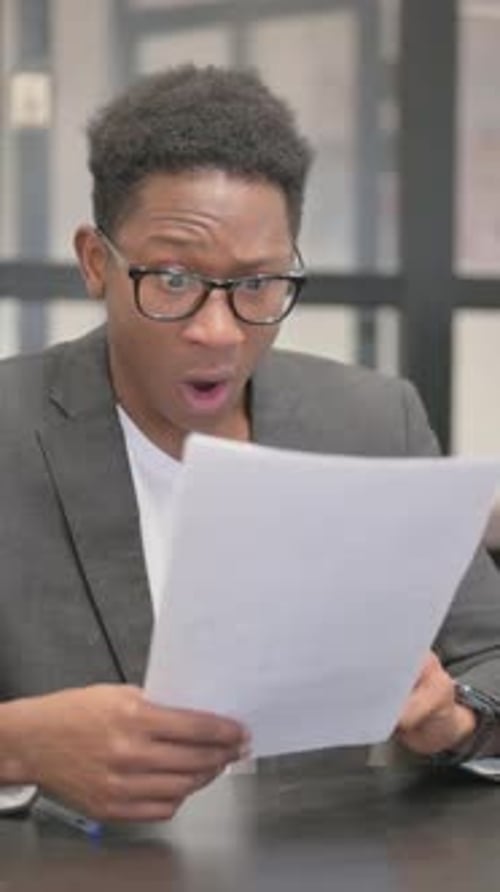 Man Reacts Negatively While Reading Documents at Office