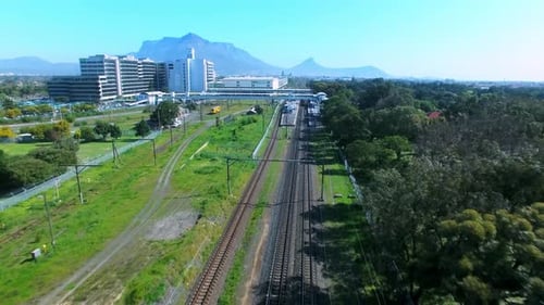 4K-Luftaufnahmen von Drohne eines Personenzugs, der auf Gleisen in der Stadt fährt