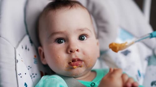 Happy Infant Eating Puree in High Chair