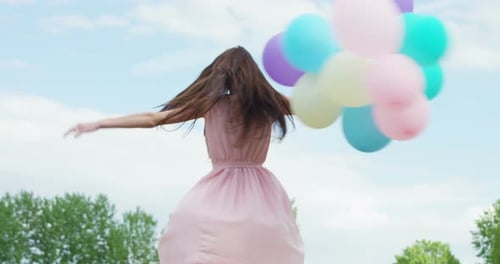 Joyful Woman Spinning with Balloons in Nature