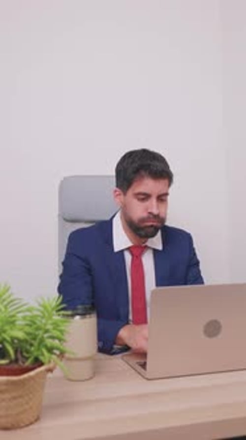 vertikal Gestresster Geschäftsmann erhält schlechte Nachrichten auf einem Laptop, der im Büro arbeitet