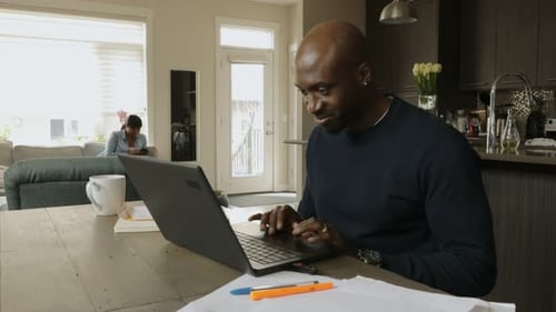 Man works at laptop on dining table telecommuting from home