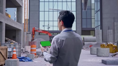 Asian Male Holds A Phone's Green Screen at Construction Site