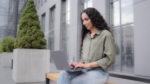 Woman Working on Laptop Outside in Urban Area