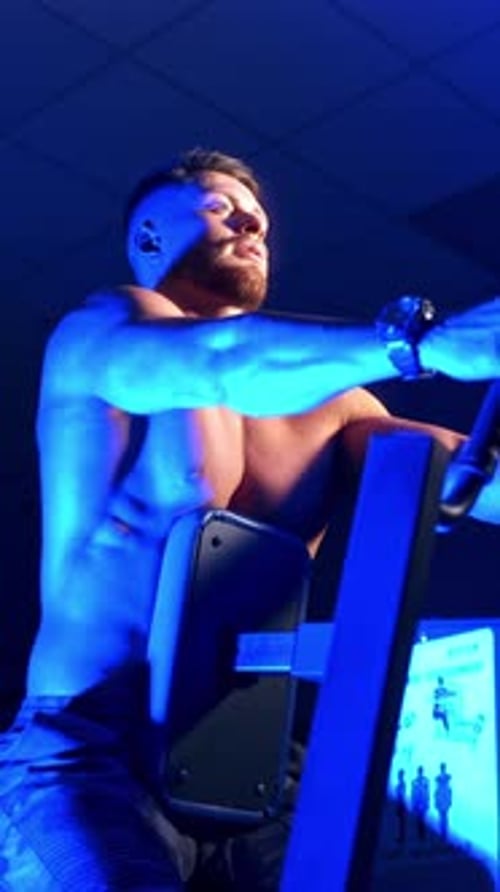 Sportsman on simulator. Shirtless athlete doing his workout in the sports club.