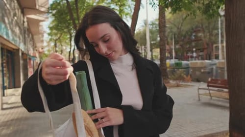 Mujer joven inspeccionando compras mientras está de pie en la calle