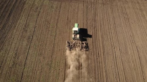 Big Powerful Tractor Plowing Farming Field in Dust and Preparing Land for Sowing