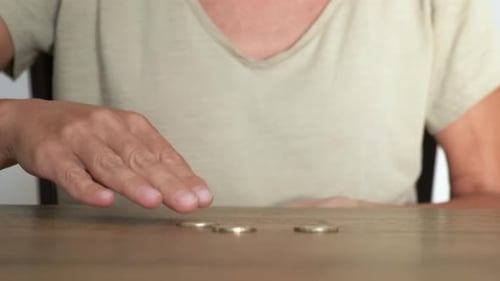 Woman Counts Gold and Silver Coins at Table