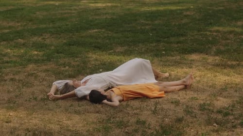 Mother and Daughter Lying on Grass in Park Enjoying Family Time Together